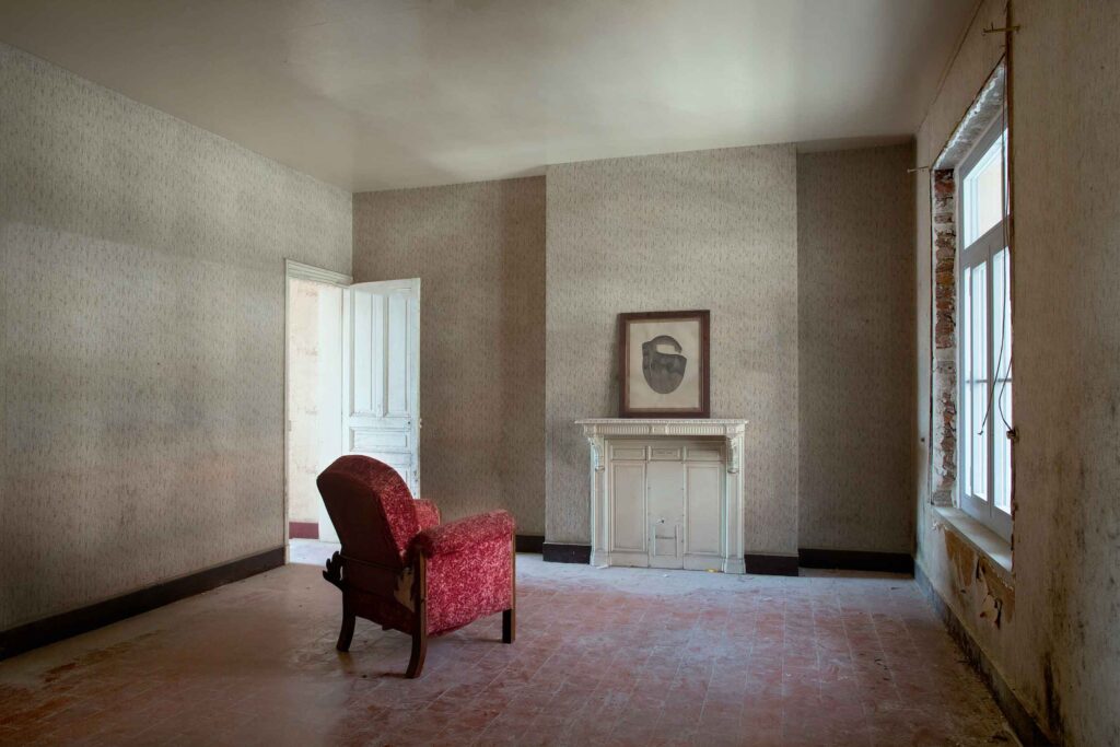 Intérieur d'un appartement du Familistère, fauteuil devant une cheminée et tableau