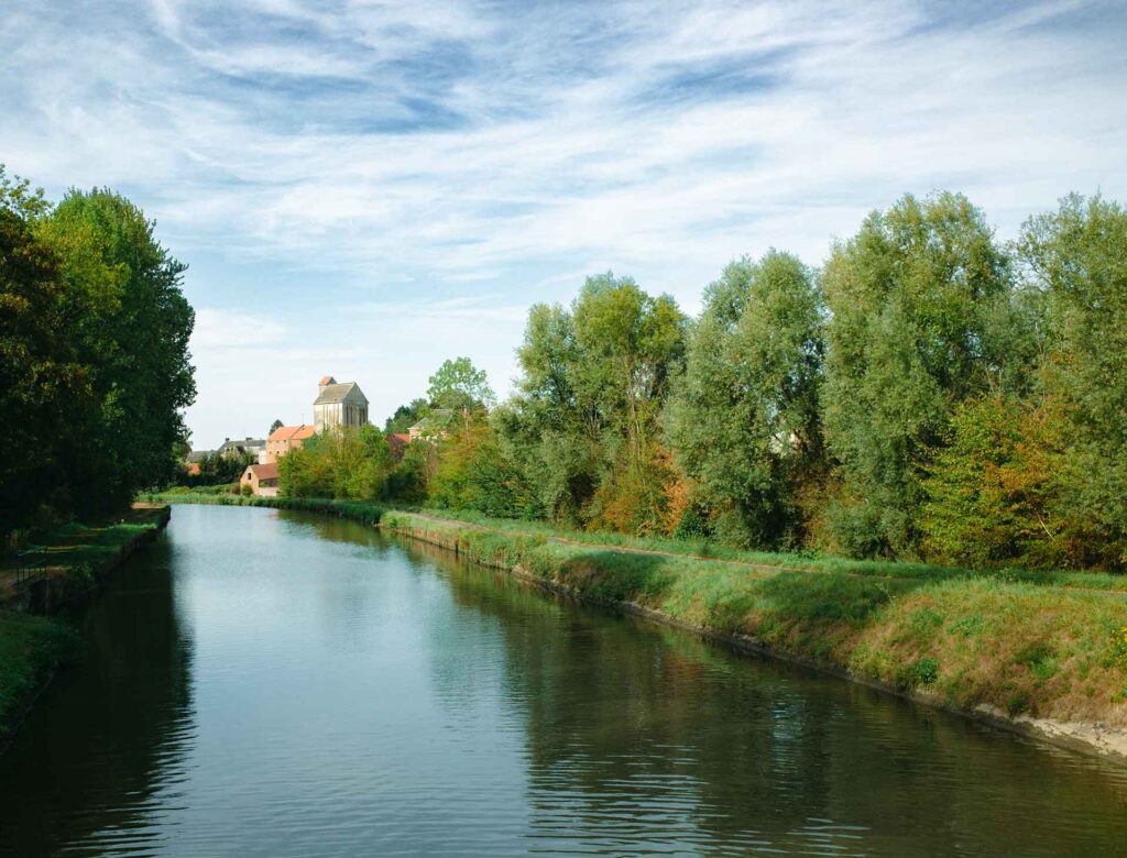 Vue sur le canal de la Sambre à l'Oise et bâtiments agricoles