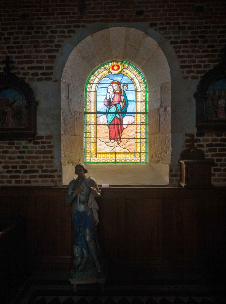 Interior of Plomion church, stained glass windows and statue